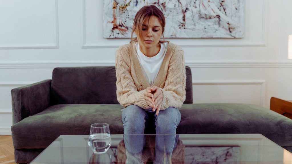 Person sitting alone with withdrawn body language, reflecting heroin addiction symptoms