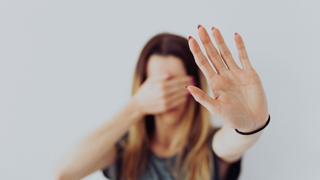 Person holding up a hand to avoid confrontation or discussion about drinking